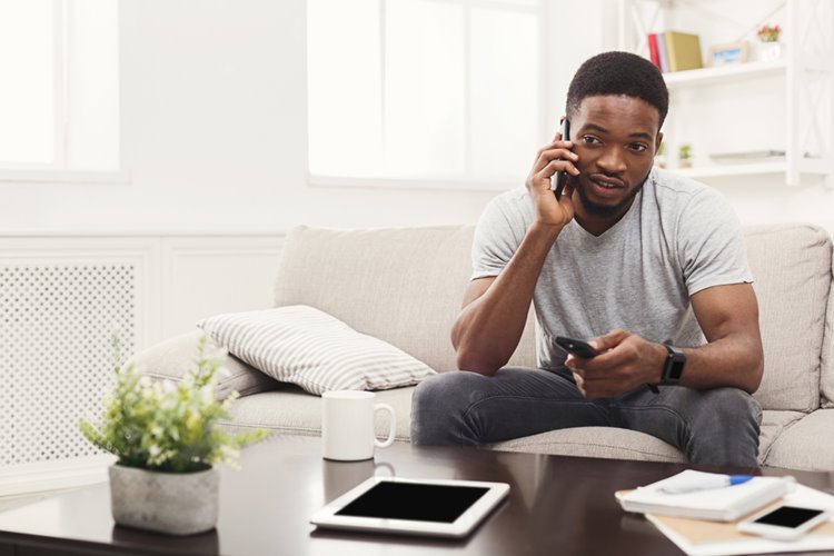 dark skinned man talking on the phone in living room