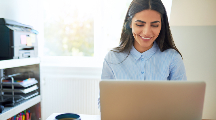 young indian woman smiling in front of laptop