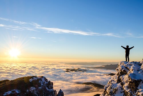 person looking at sunrise after hiking on top of mountain