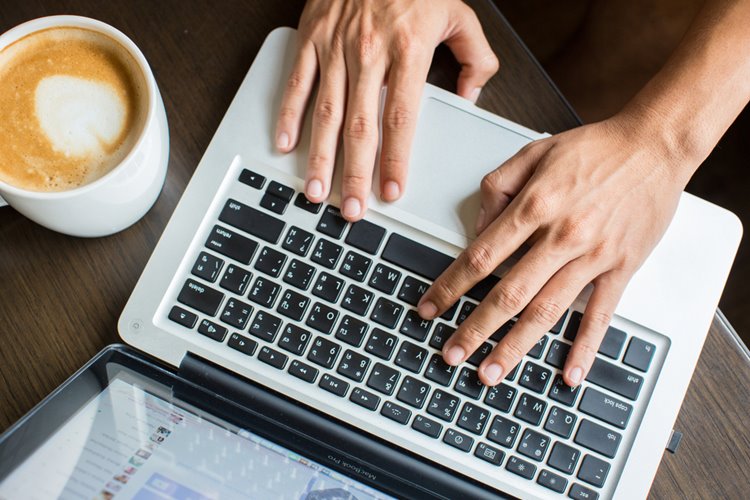 man working on laptop at cafe, having coffee