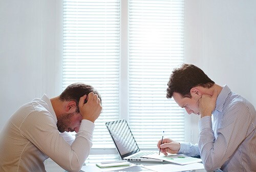 male colleagues looking down and frowning at work