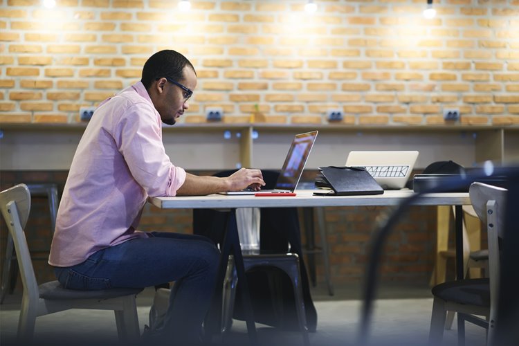 dark-skinned male IT programmer working on laptop