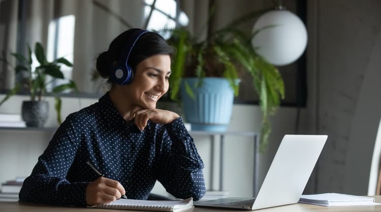 woman smiling at laptop with headphones