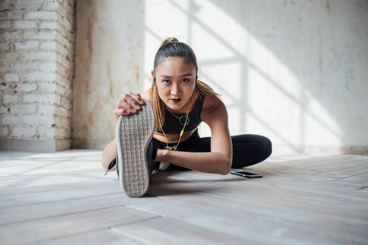 young asian woman stretching in gym gear