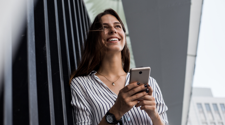 young woman smiling while messaging on phone