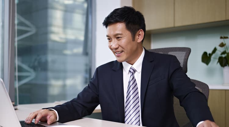 asian man happily working on laptop