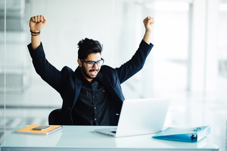 man with arms in the air facing laptop