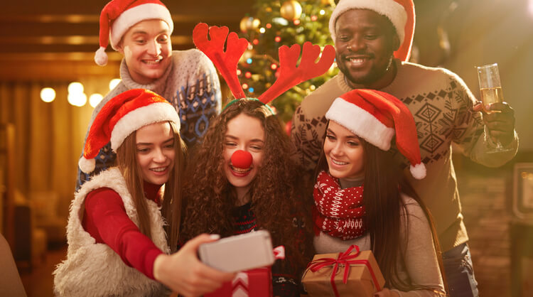 group of young adults in christmas attire taking a selfie