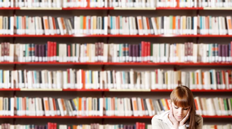 young woman looking stressed studying at library