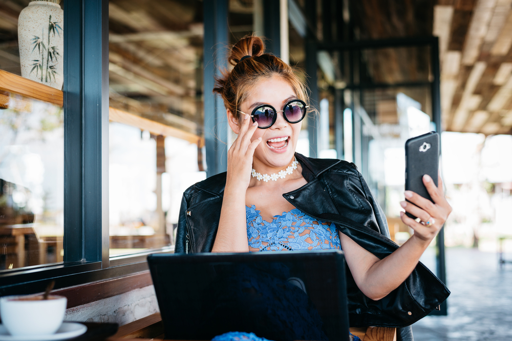 brunette haired woman with sunglasses working on laptop