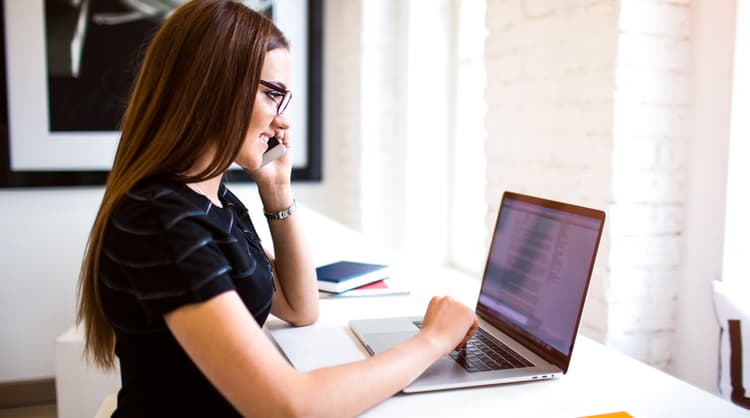 woman having a chat on the phone while on laptop