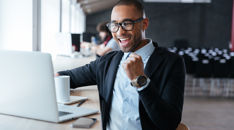 african american with glasses cheering in front of laptop