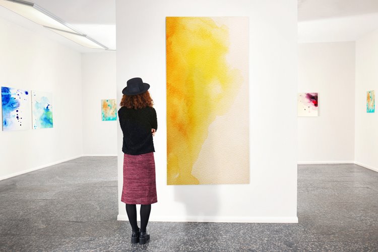 young woman looking at painting in art gallery