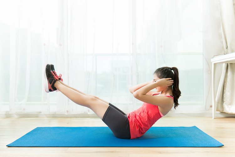 asian woman doing sit ups on yoga mat