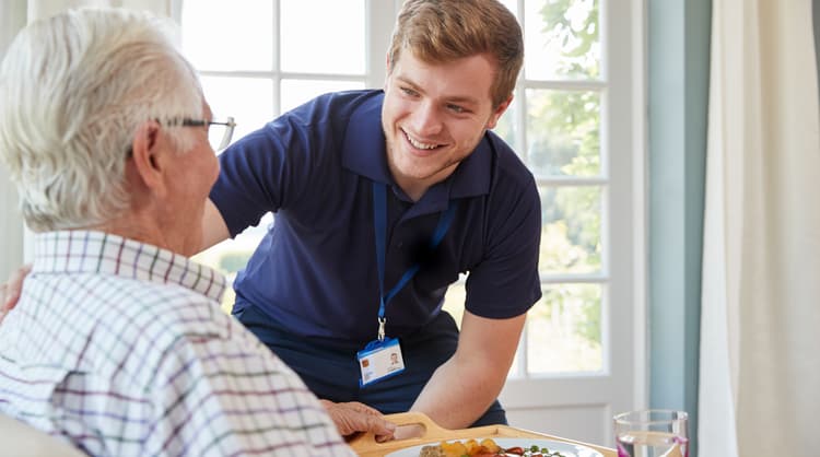 male care worker assisting elderly woman