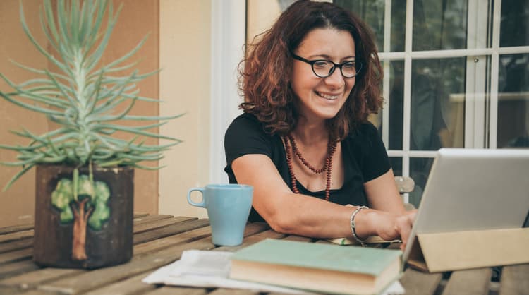 middle aged woman smiling and typing on laptop