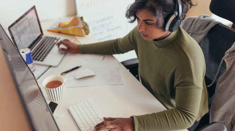 woman programmer working on laptop and desktop computer