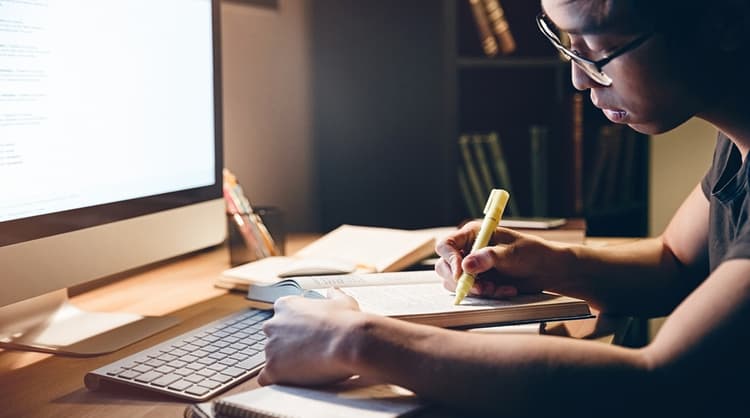 young asian man studying in front of computer