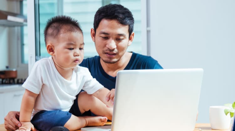 asian man working from home with baby son