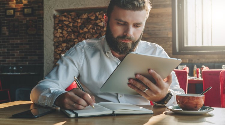 bearded young man reading on tablet