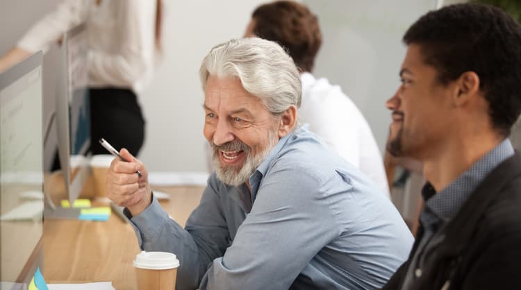 senior man employee teaching younger male employee