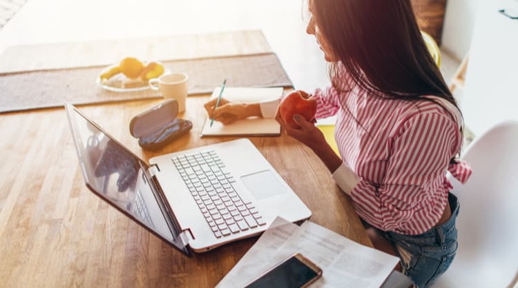 young woman budgeting and eating apple