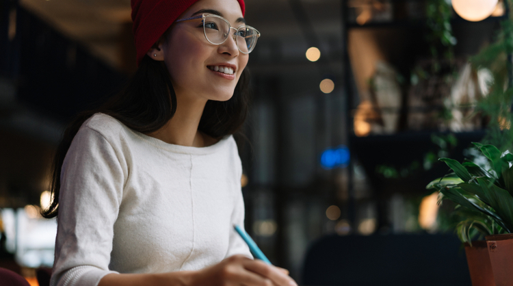 young asian woman with glasses smiling and working on something