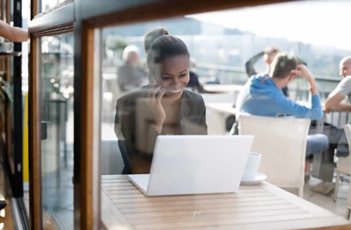 dark skinned woman working at restaurant with laptop