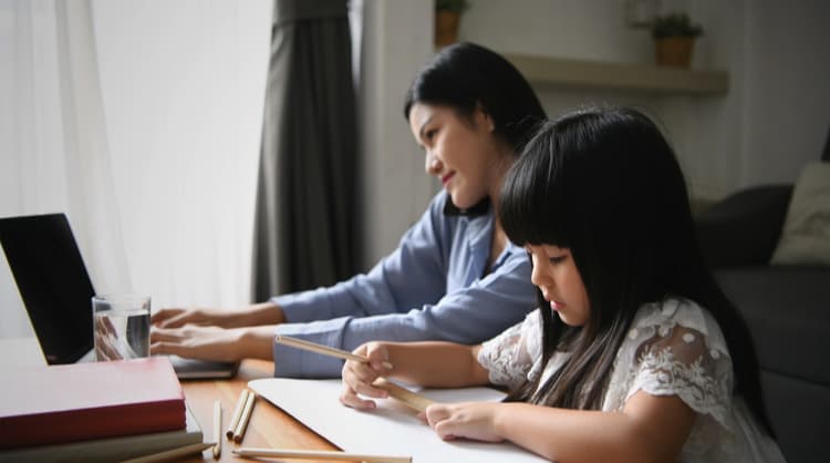 woman working from home while child draws