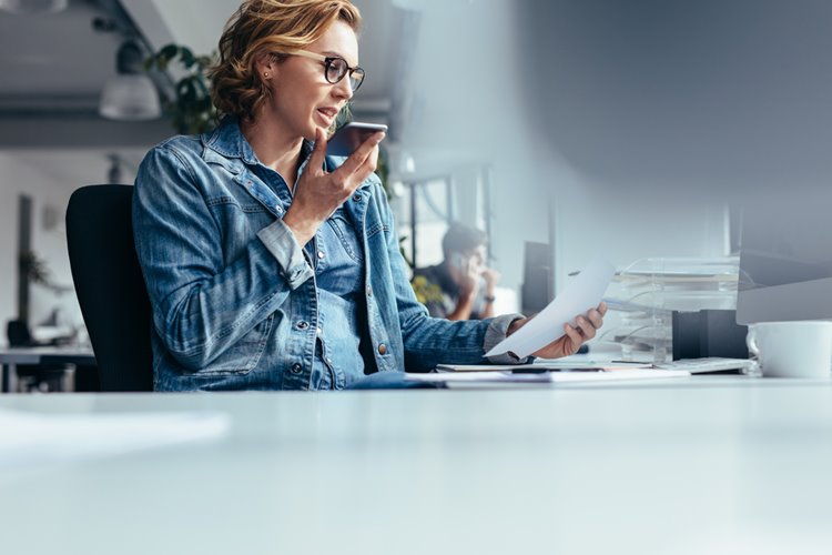 caucasian woman in glasses speaking to virtual assistant