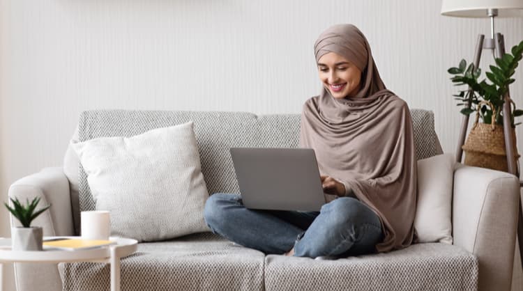 woman looking at laptop on couch