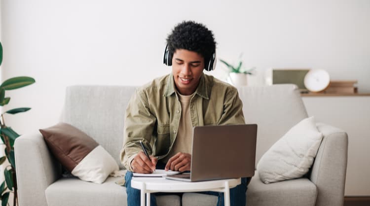 young man studying online, listening to headphones