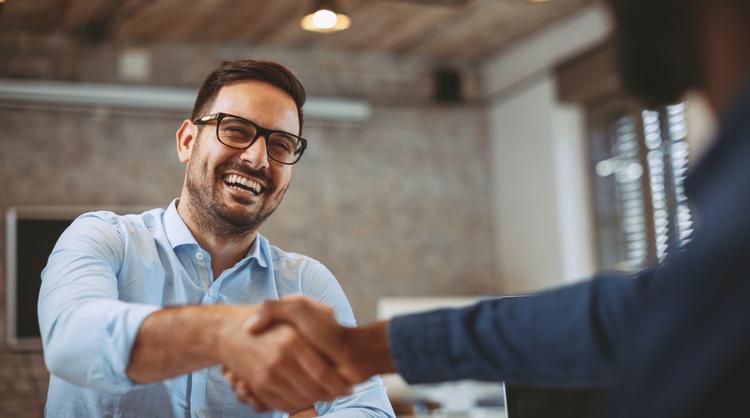 guy with glasses grinning while in a handshake