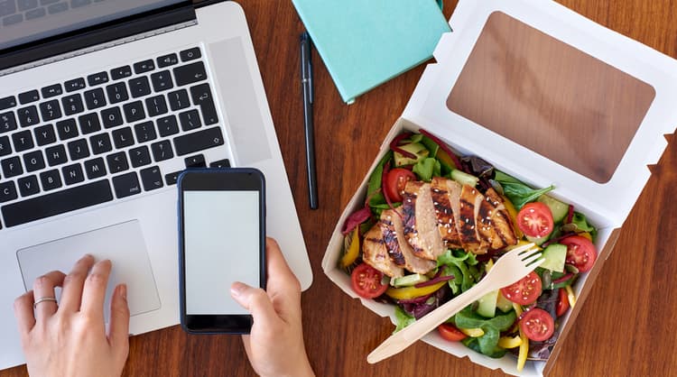 person working from home and eating takeaway salad