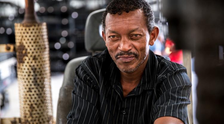 african american older man smiling driving forklift