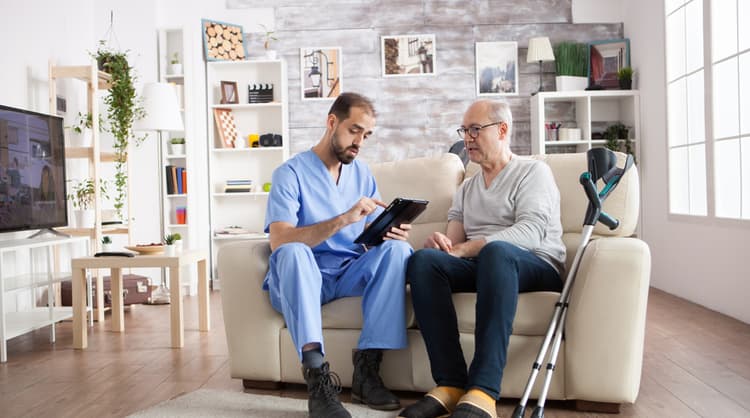 male aged care worker talking to elderly man at home