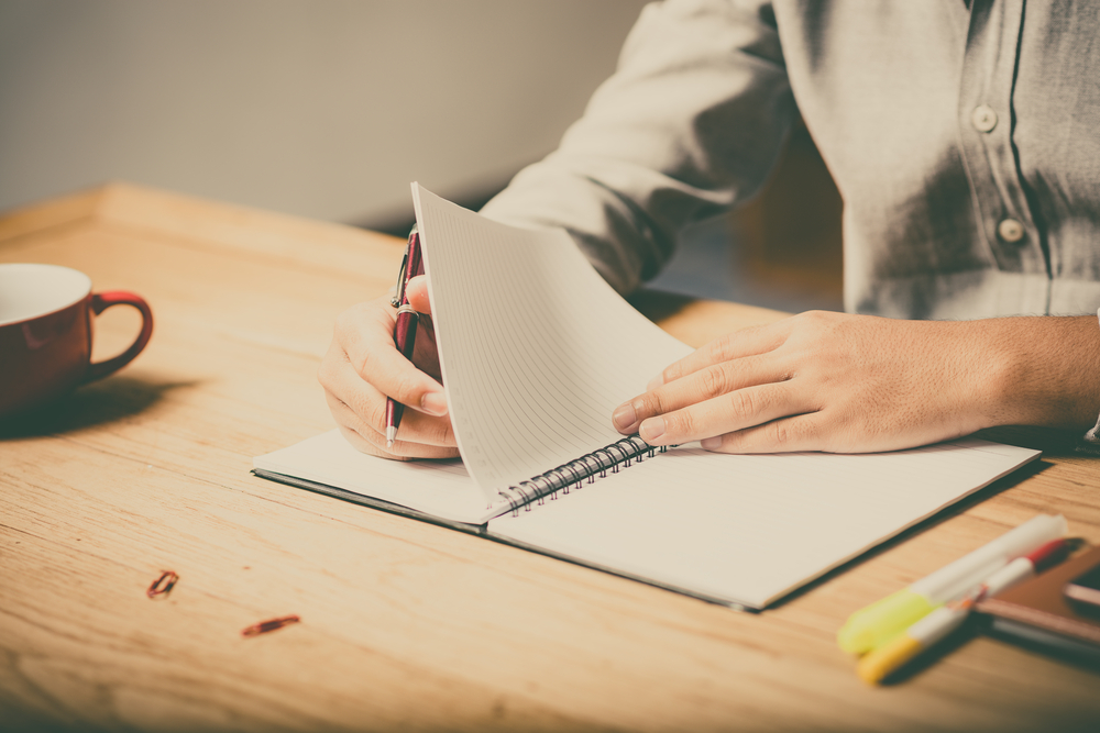 man writing in notebook