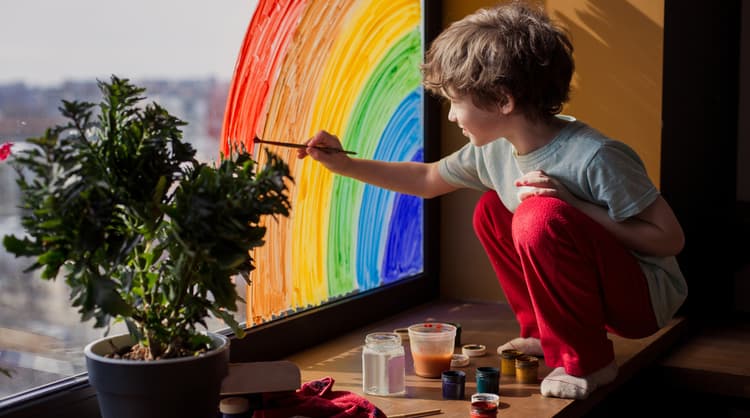 young boy painting rainbow