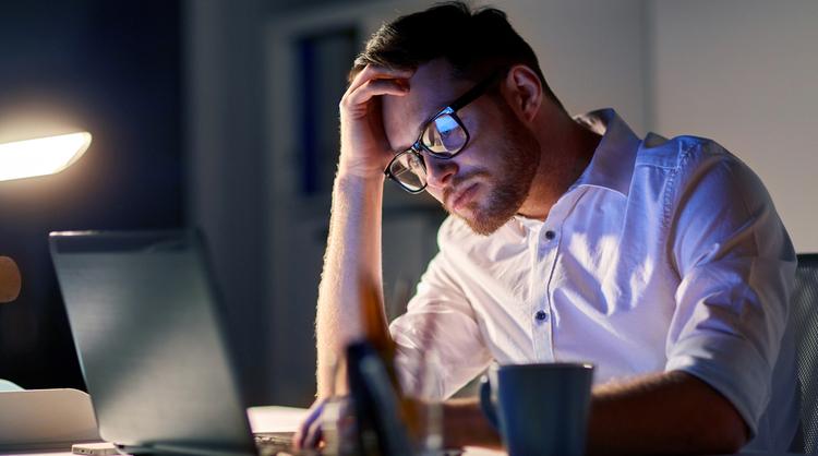 man staring at laptop looking stressed